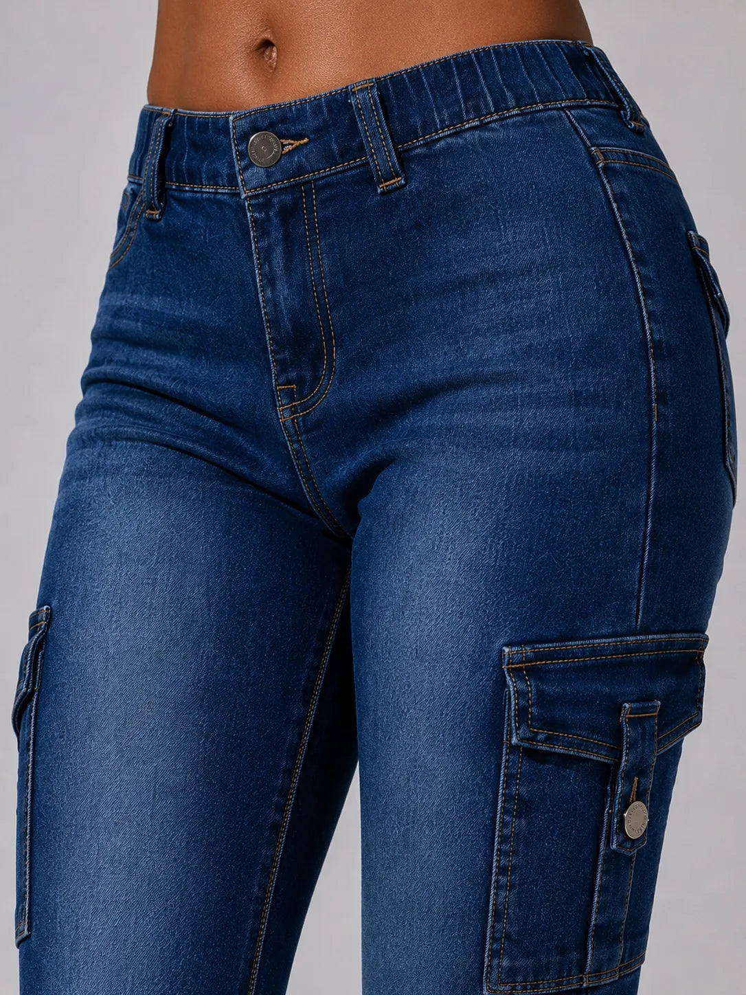 Close-up of the waist and cargo pocket of dark wash blue flare jeans.