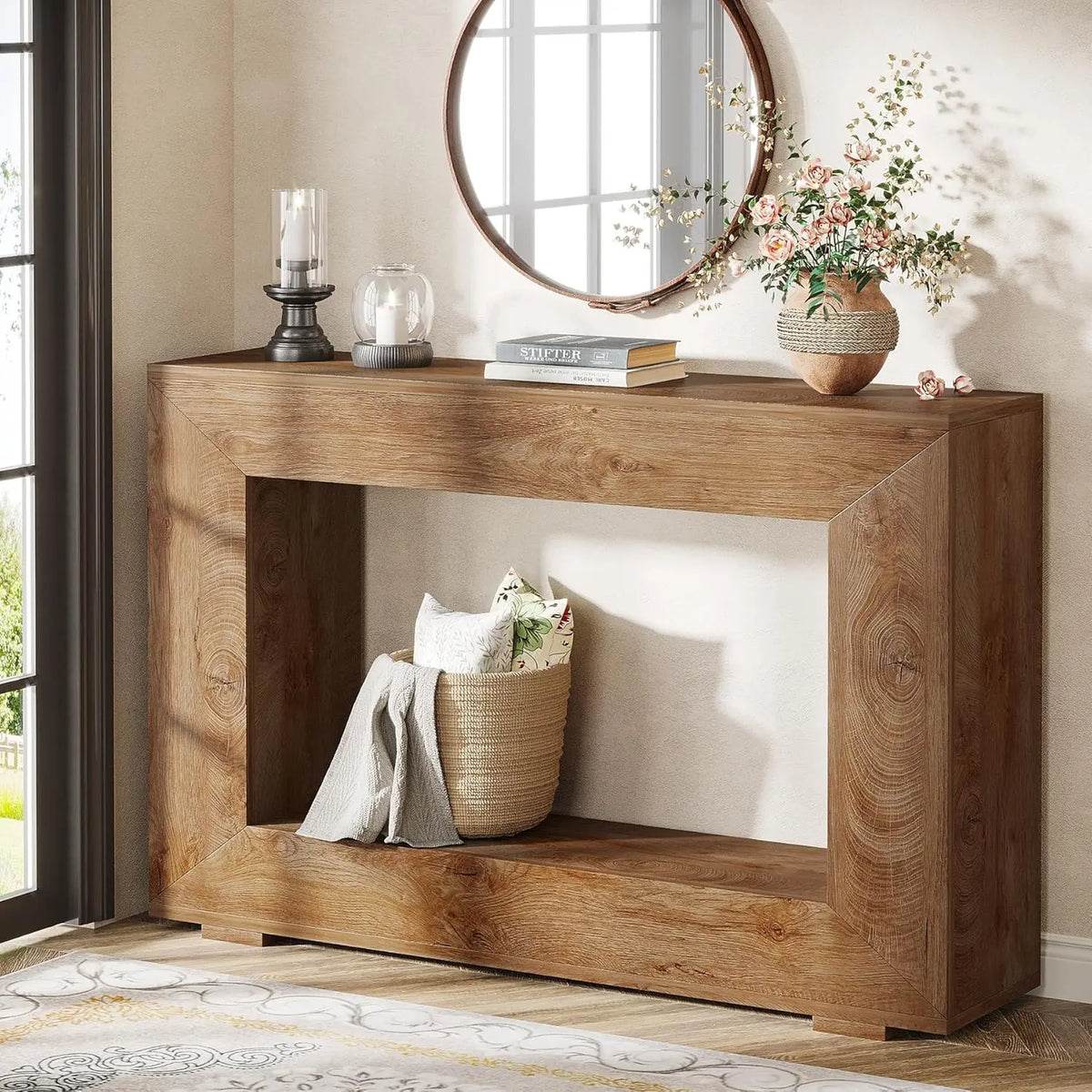 A rustic brown wooden console table in an entryway with decor including a mirror, a basket, and a flower vase.