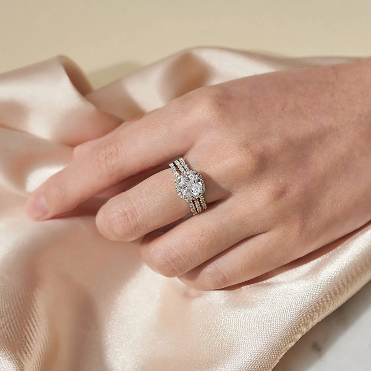 Woman wearing a cushion cut halo engagement ring set with matching bands on her finger