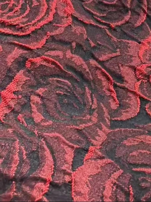 Close-up detail of textured red and black rose floral embroidery fabric