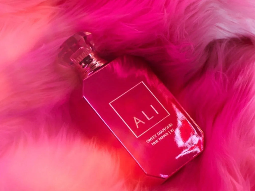Pink diamond-shaped perfume bottle placed on a fluffy pink texture background
