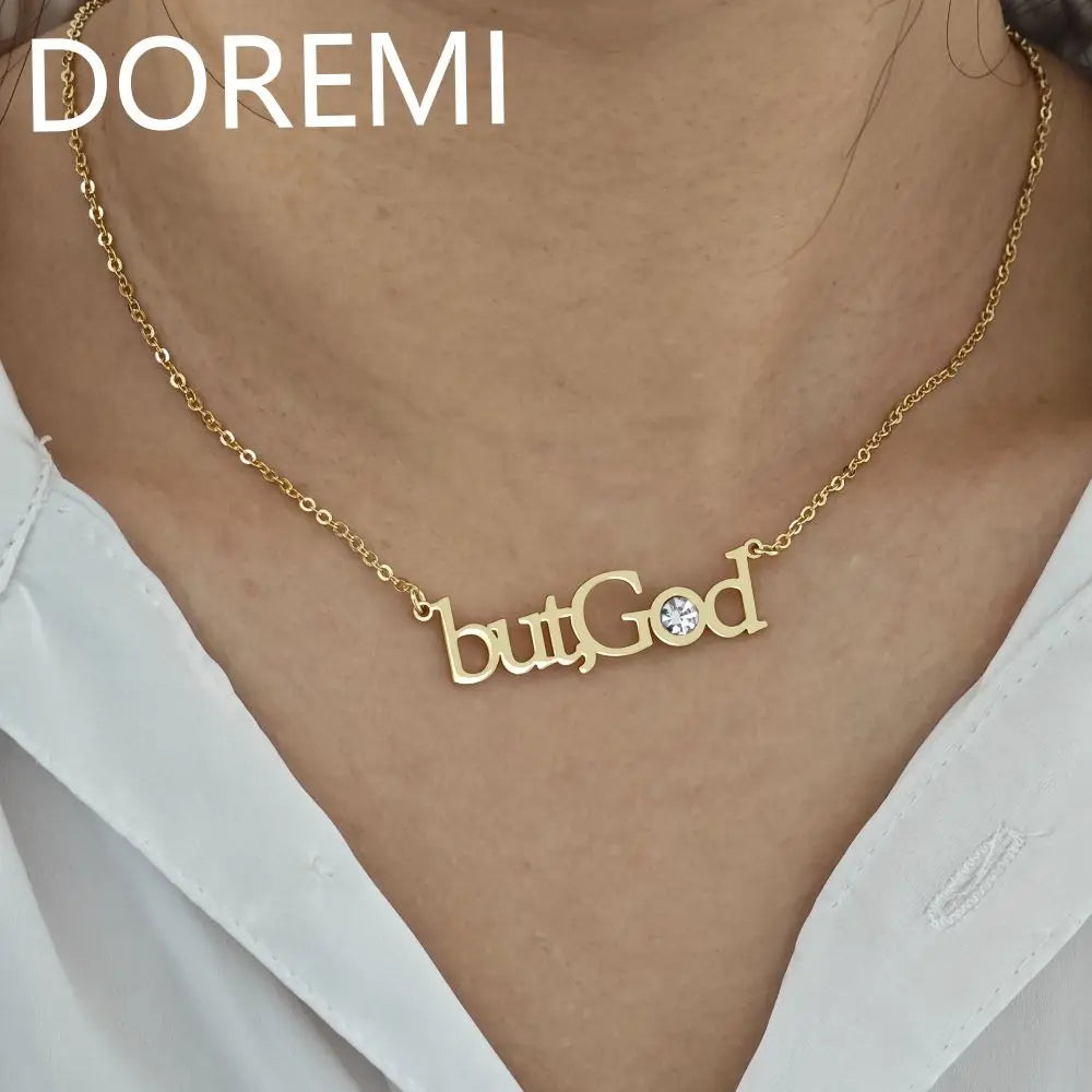 Gold necklace featuring the words butGod with a small crystal detail worn by a person
