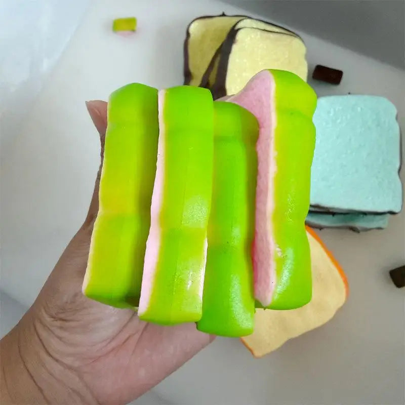 A person holding green and pink toast shaped squishy toy