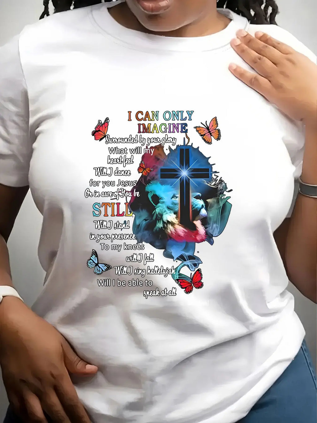 A white short-sleeved crew neck t-shirt with a religious graphic print featuring a cross, lion, butterflies, and lyrics