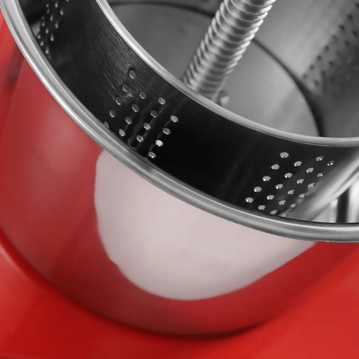 Close up detail of the stainless steel inner perforated basket of a fruit and herb press
