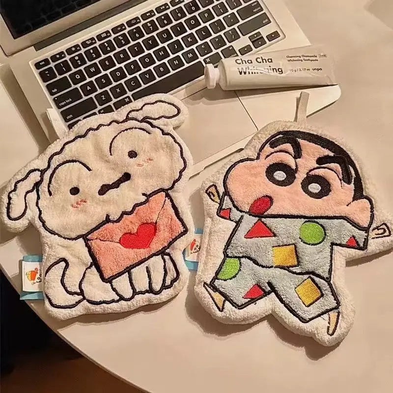 Two cartoon-themed hanging hand towels shaped like a dog and a boy resting on a laptop keyboard.