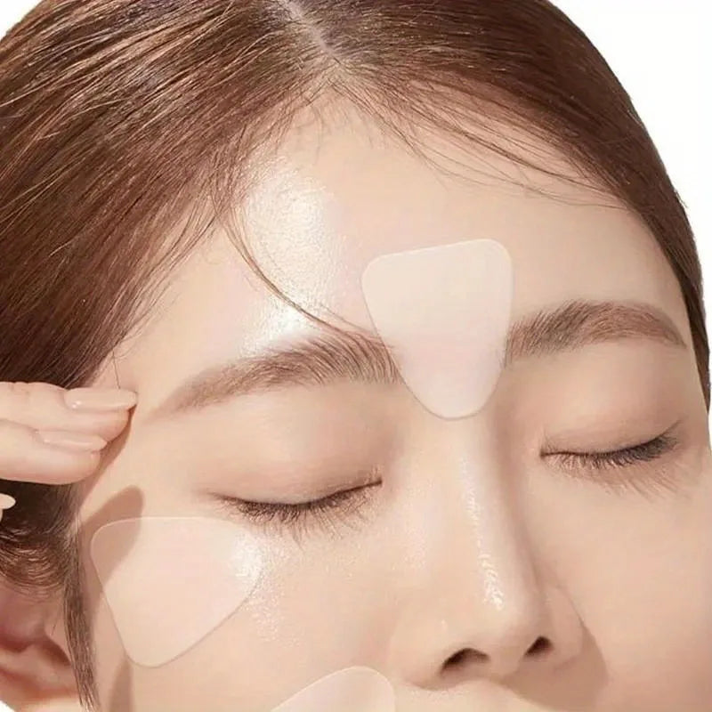 A close up of a face with transparent triangular anti-wrinkle patches applied to the skin.