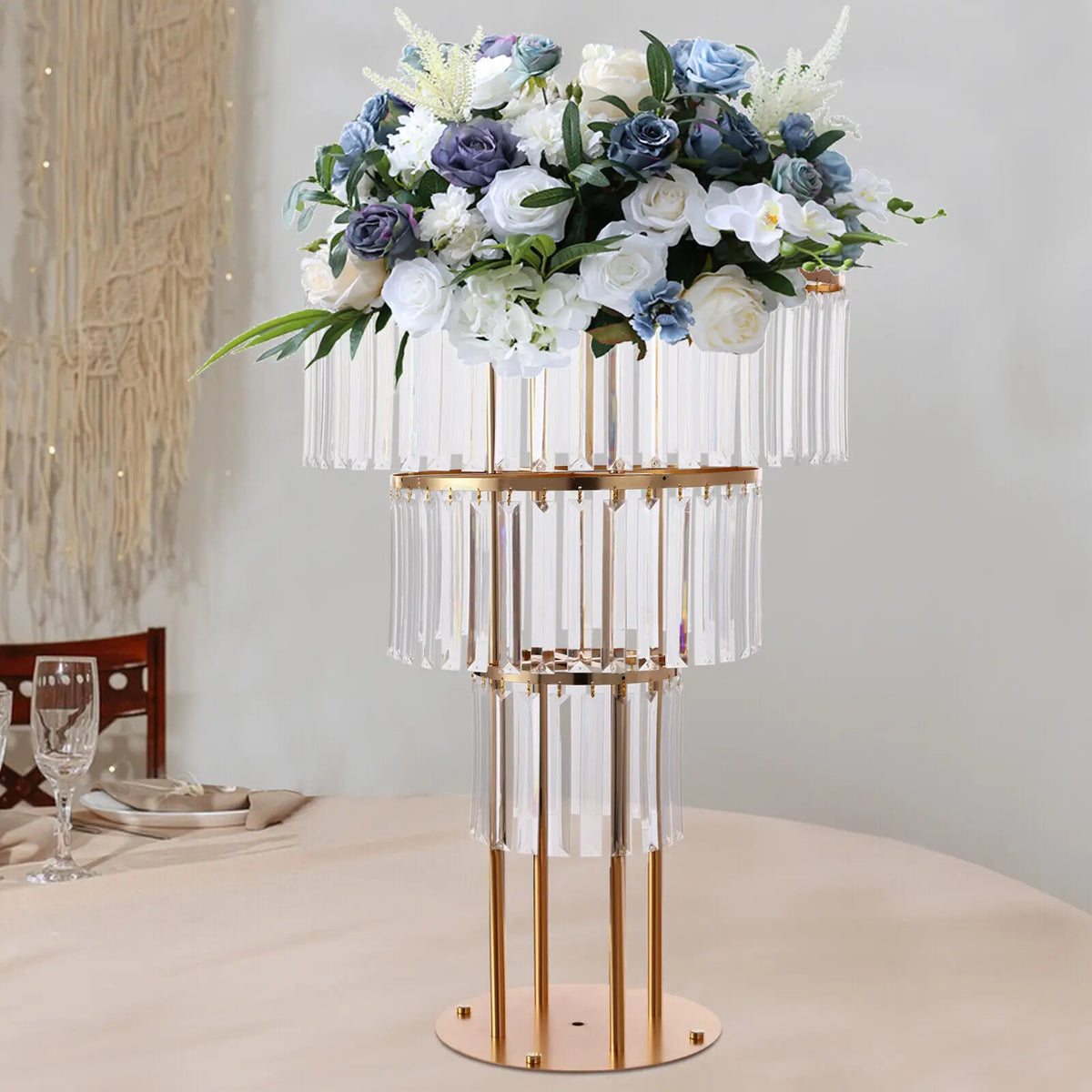 A three-tier gold metal and crystal flower stand with a floral arrangement on a dining table.