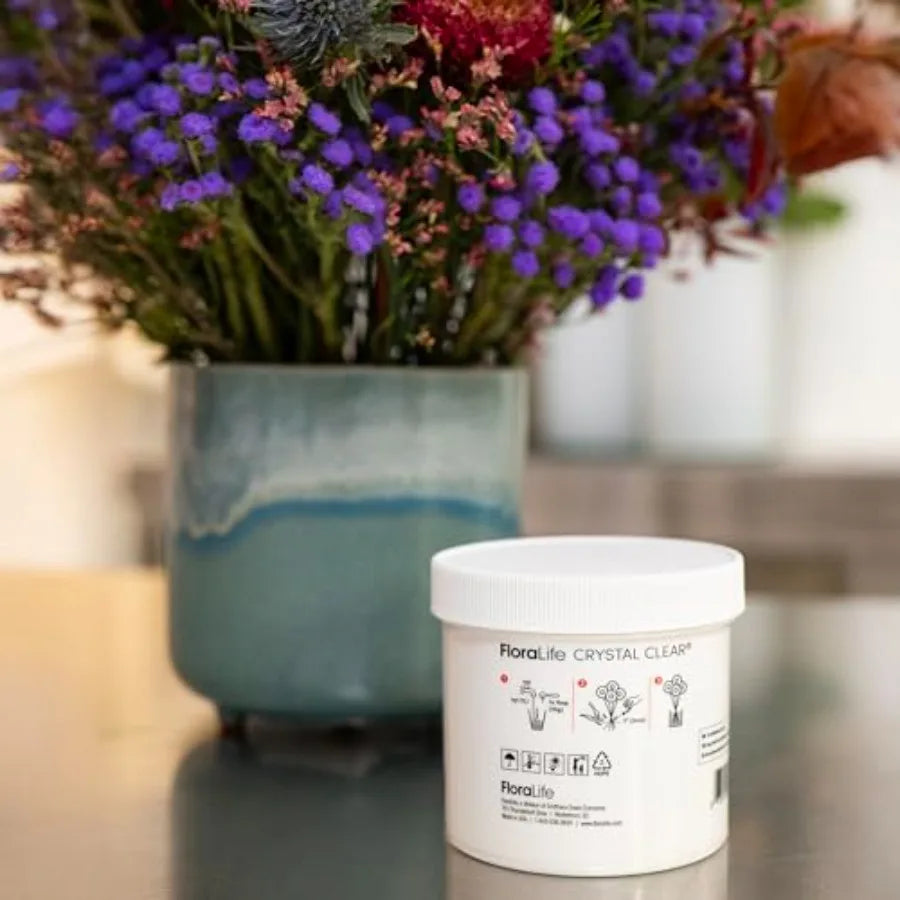 Close-up of the back of a flower food powder container showing instructions, next to a blue vase with flowers