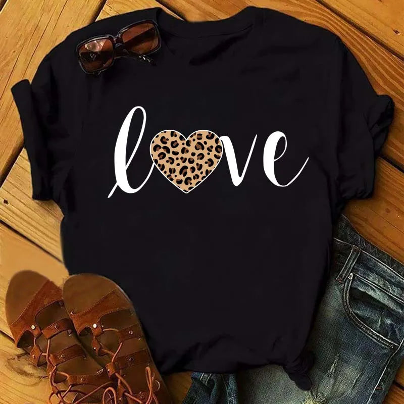 Black short sleeve t-shirt with leopard print heart graphic on wooden background with sunglasses and sandals