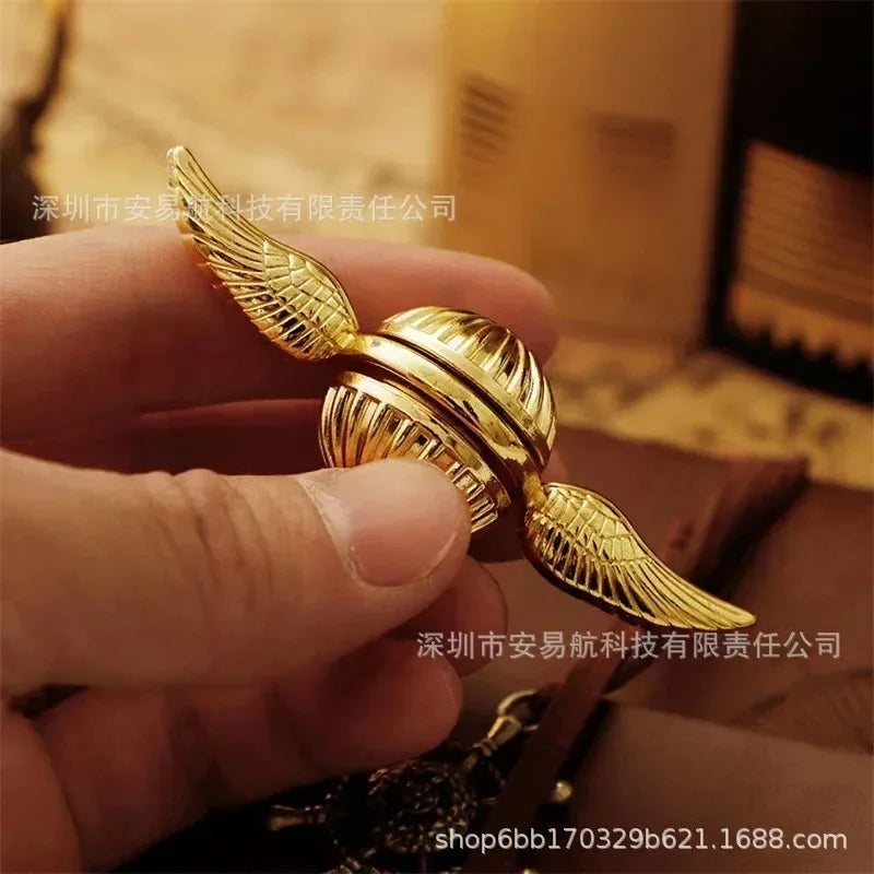 Golden snitch fidget spinner held in hand showing intricate wing design