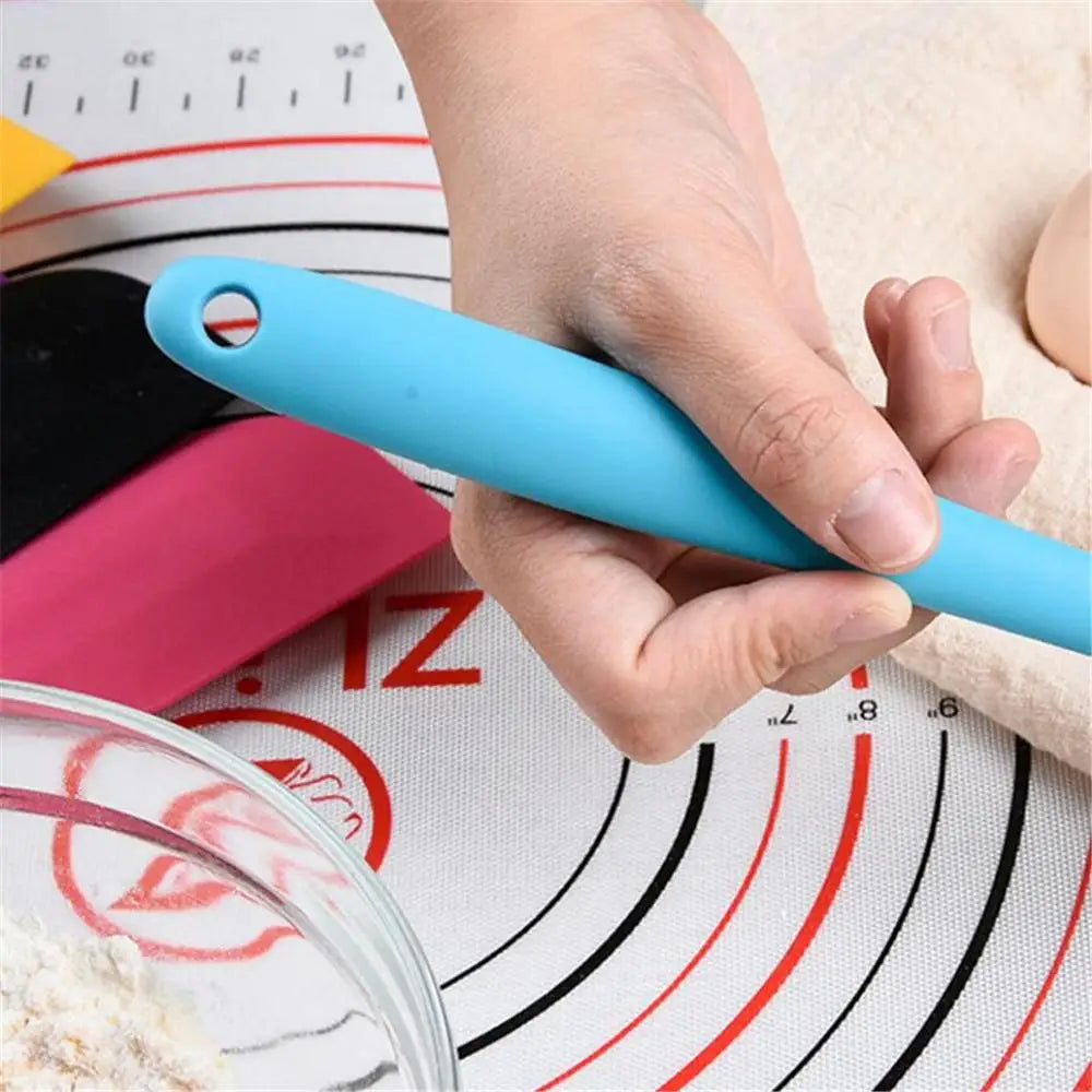 Close-up of a hand holding a blue silicone spatula with a baking mat in the background.