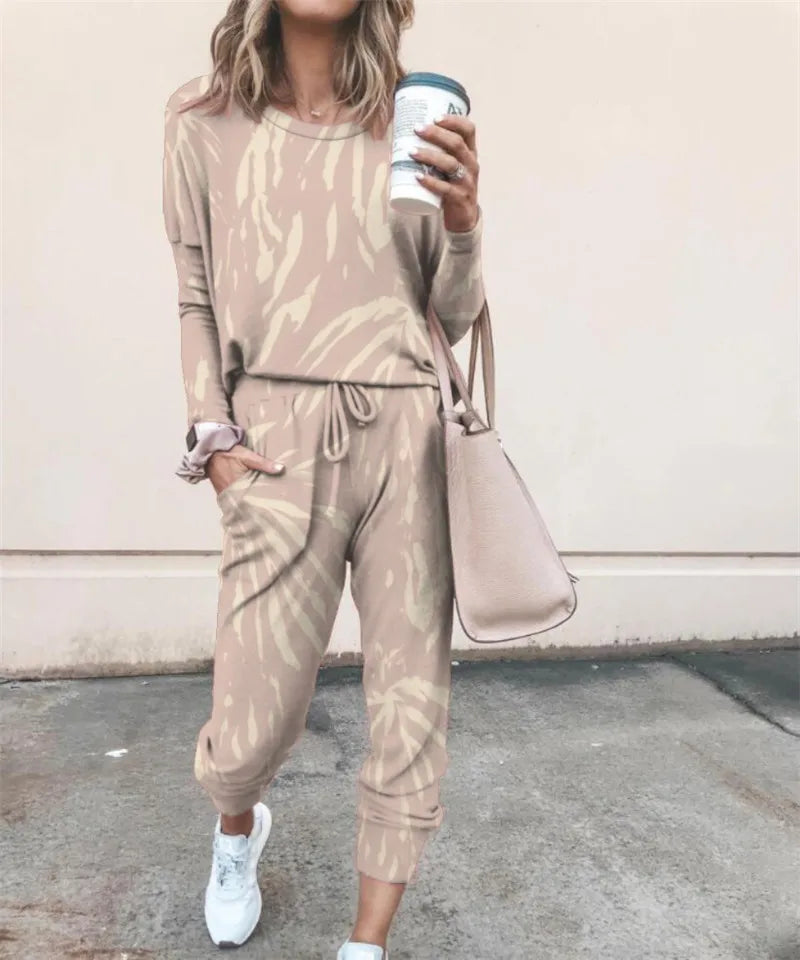 A woman wearing a beige and cream tie-dye long-sleeve top and jogger pants set, holding a takeaway coffee cup.