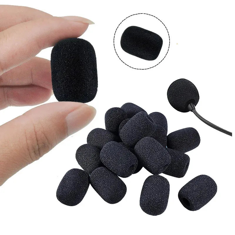 Close-up hand holding a black foam microphone windscreen cover with pile of covers below