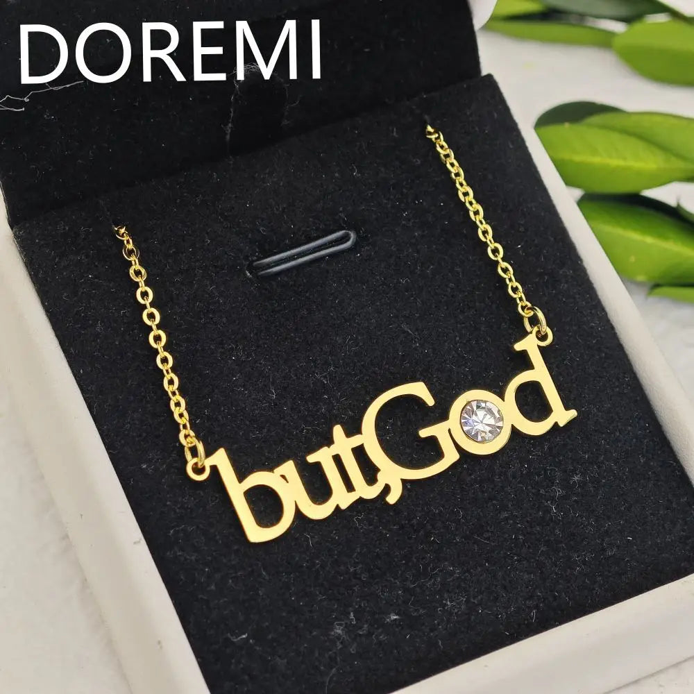 Gold necklace with the words butGod and a crystal in a black jewelry box