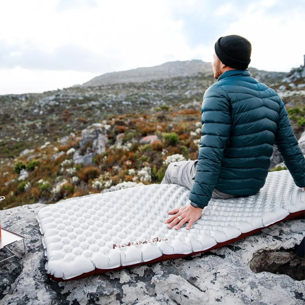 Person sitting on a sleeping pad outdoors