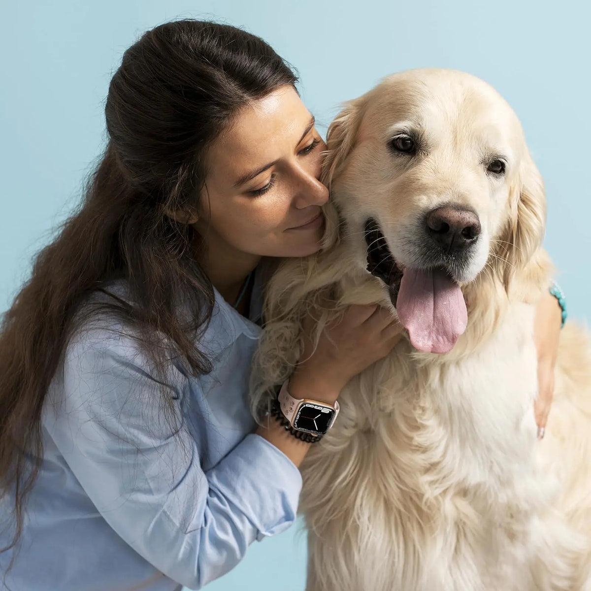 Woman wearing a pink silicone watch band hugging a golden retriever