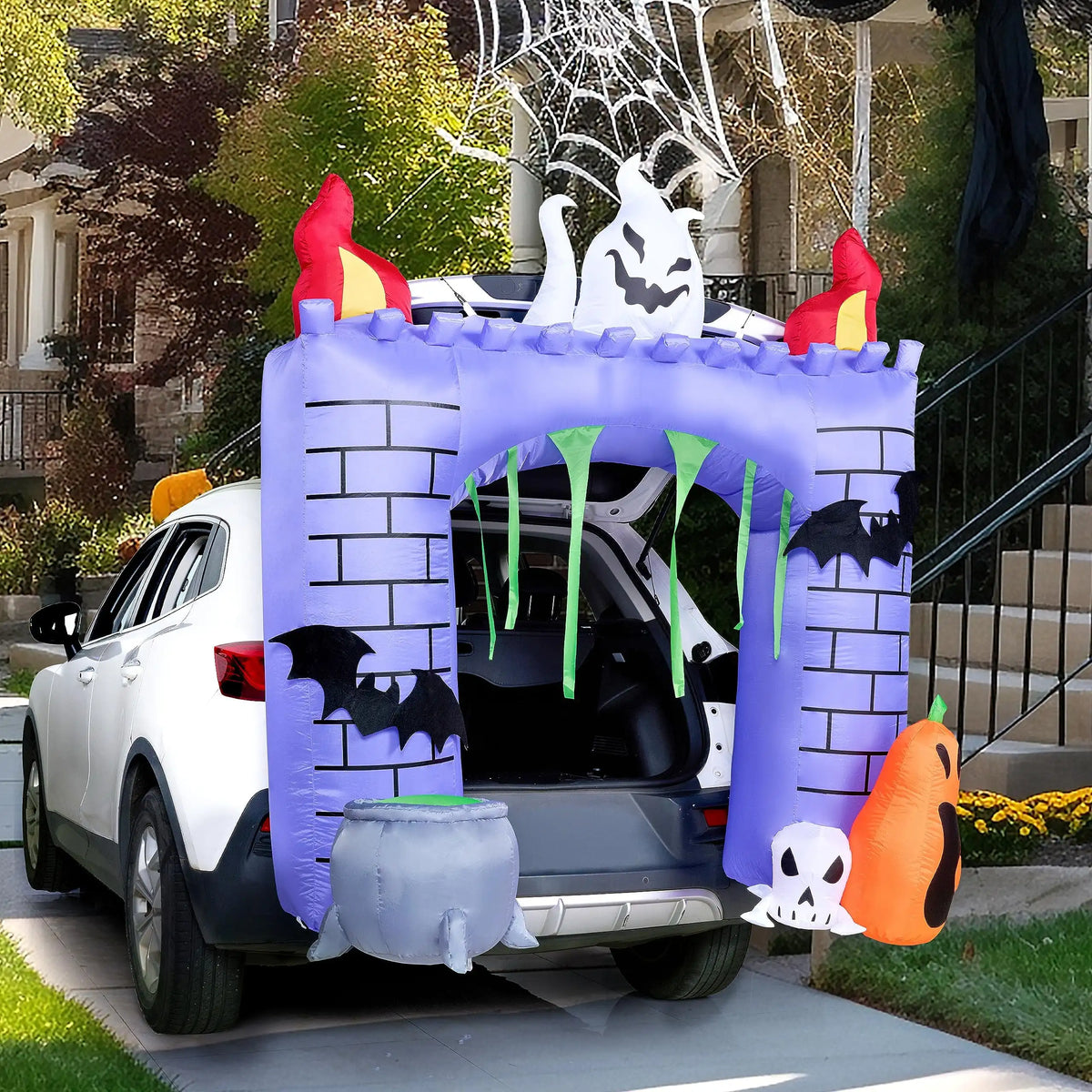 Halloween haunted castle trunk-or-treat inflatable attached to a white car in a driveway