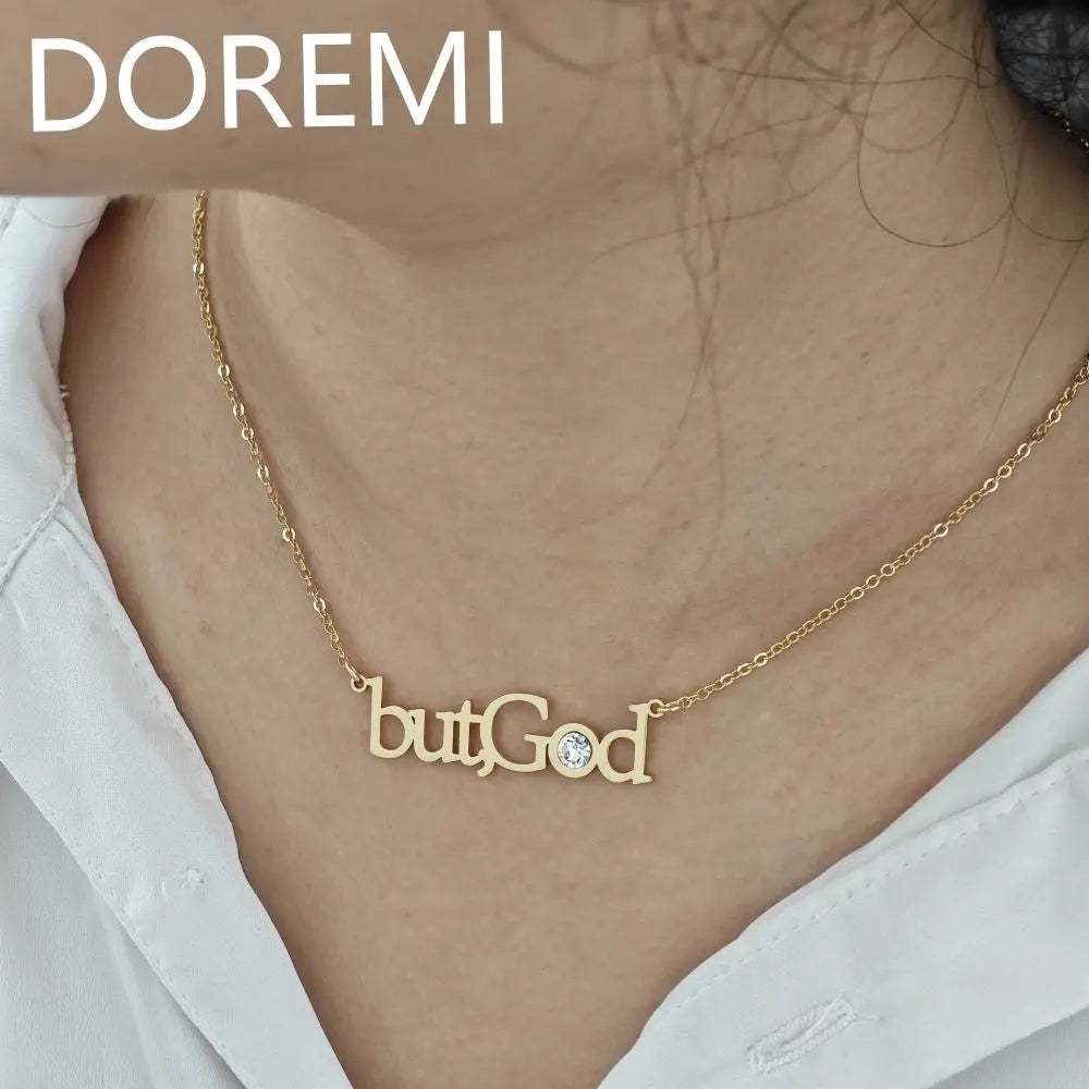 Gold necklace featuring the words butGod with a small crystal detail worn by a person