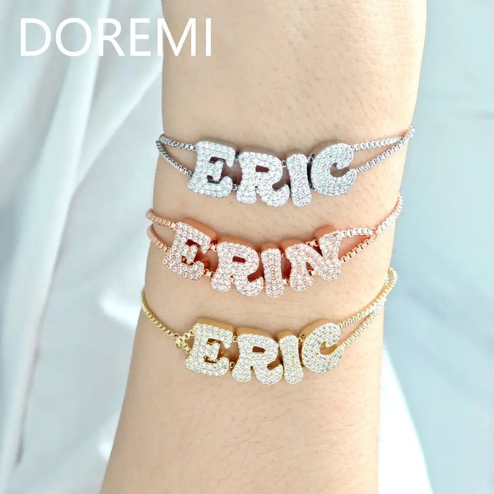 Set of three custom alphabet letter slider bracelets in silver, rose gold, and gold tones worn on a wrist.