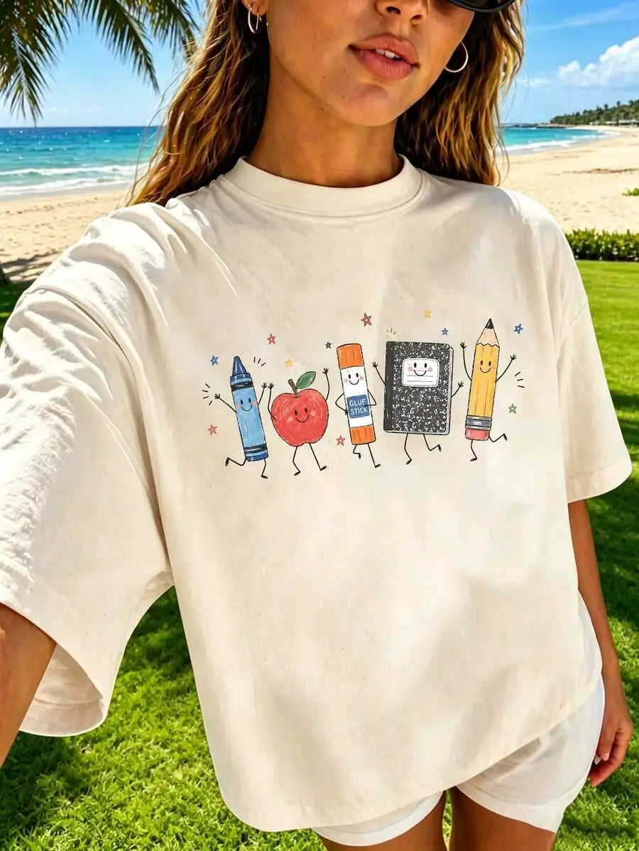 A person wearing a cream-colored t-shirt with a cute school supplies cartoon graphic at the beach.