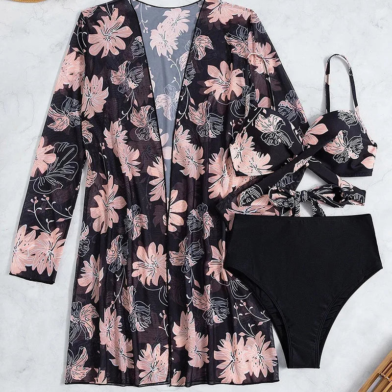 Black and pink floral bikini set with a long-sleeve mesh cover-up laid flat.