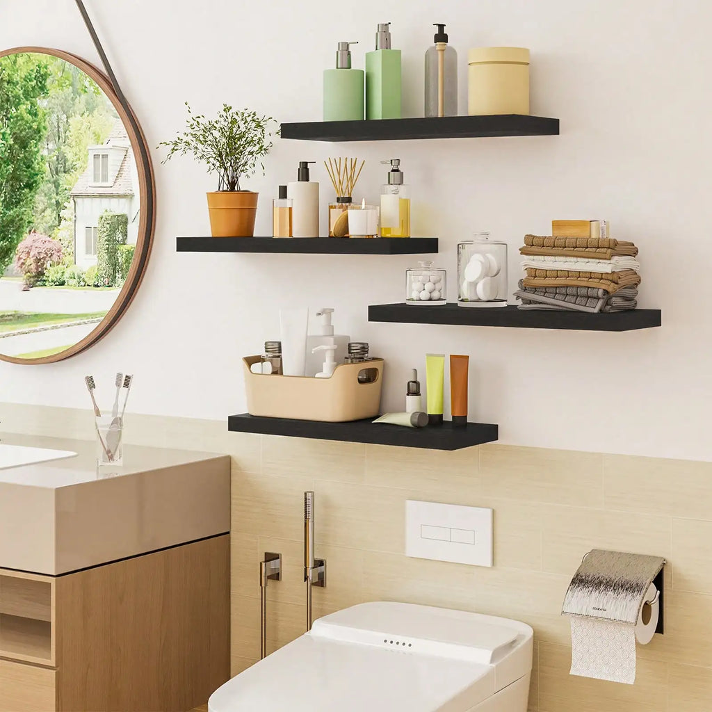Four black floating shelves installed in a bathroom above a toilet, holding toiletries, plants, and folded towels
