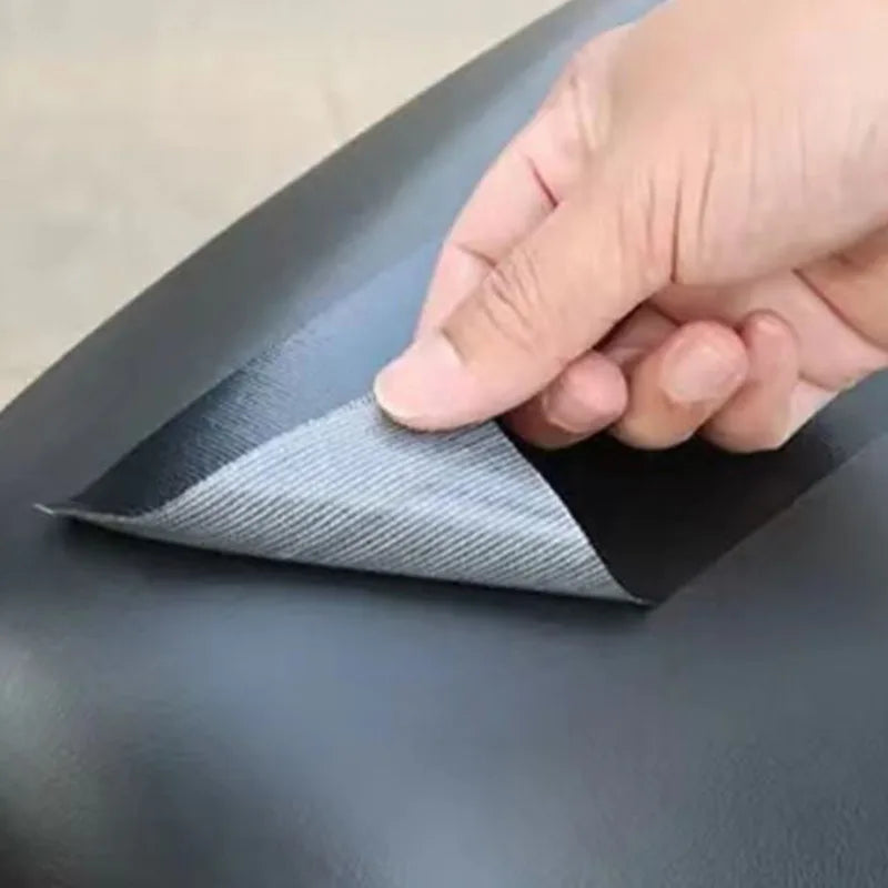 Close up of a hand applying a black adhesive leather repair patch