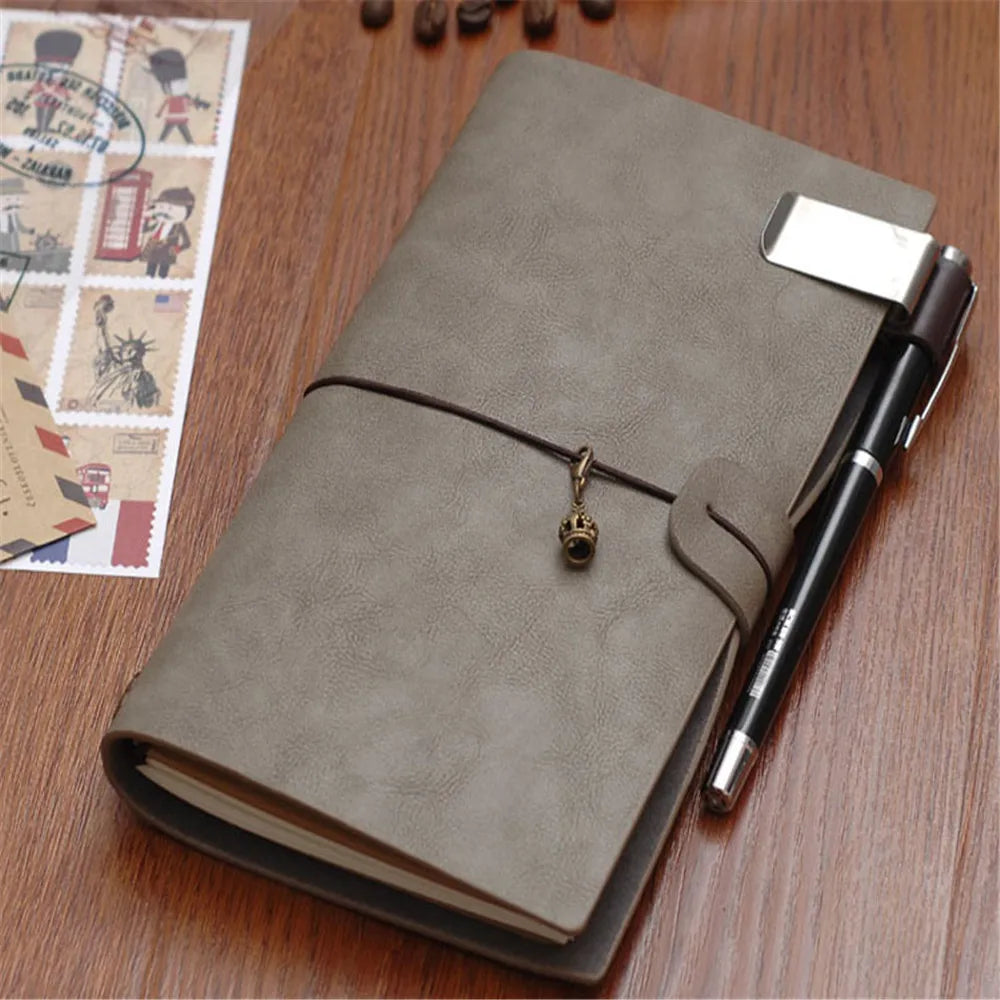 A metal and leather pen holder clip on a grey leather-style journal.