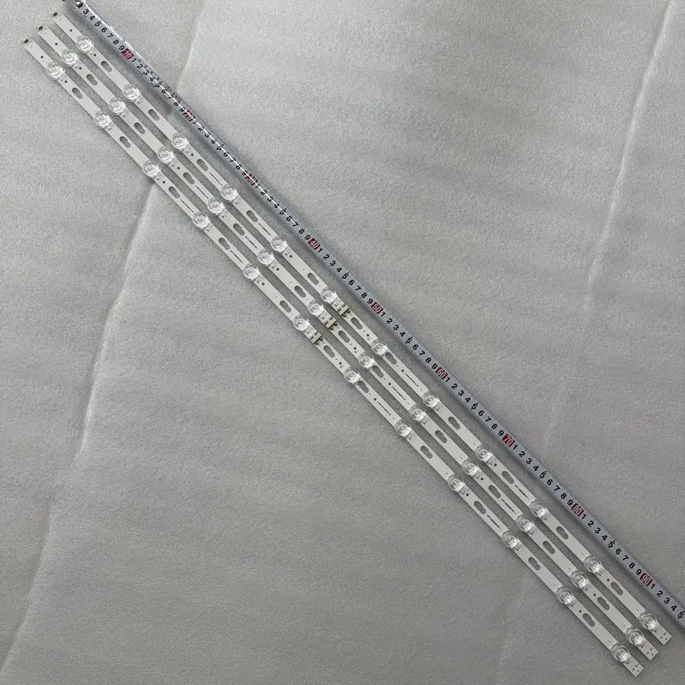 A set of white LED backlight strips placed next to a measuring tape to show their length.