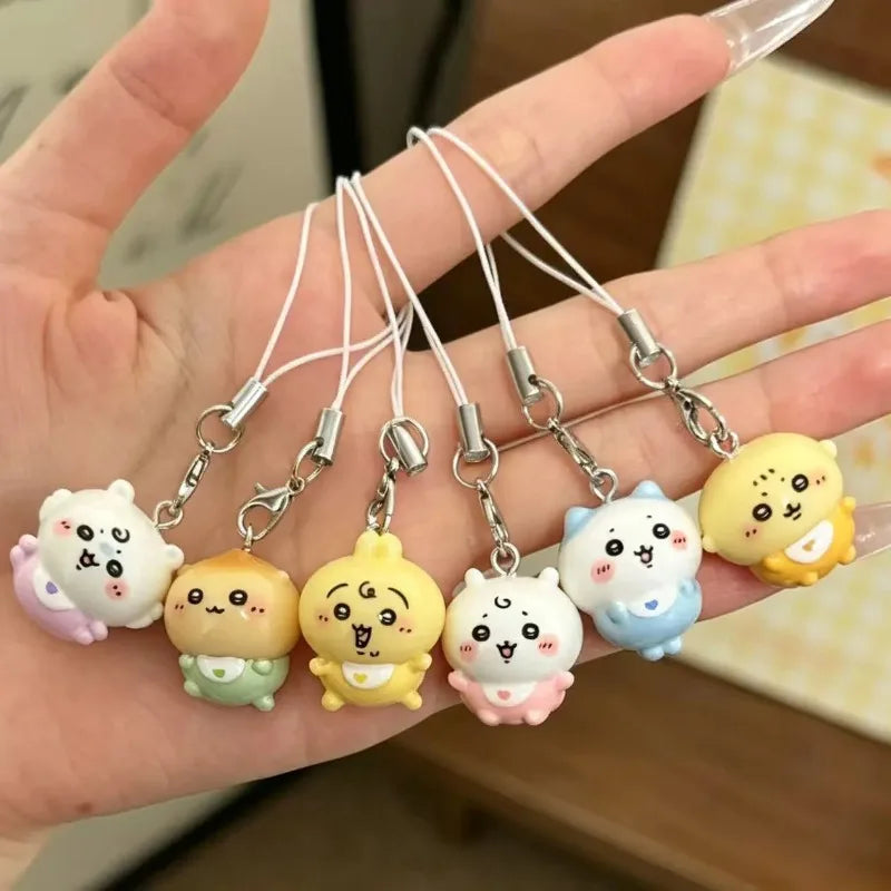 A hand holding a set of small character phone charms with lanyards.