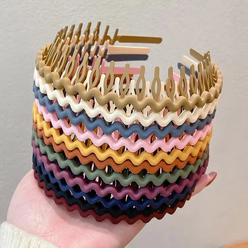 A stack of various colorful wavy, toothed hair combs in a hand