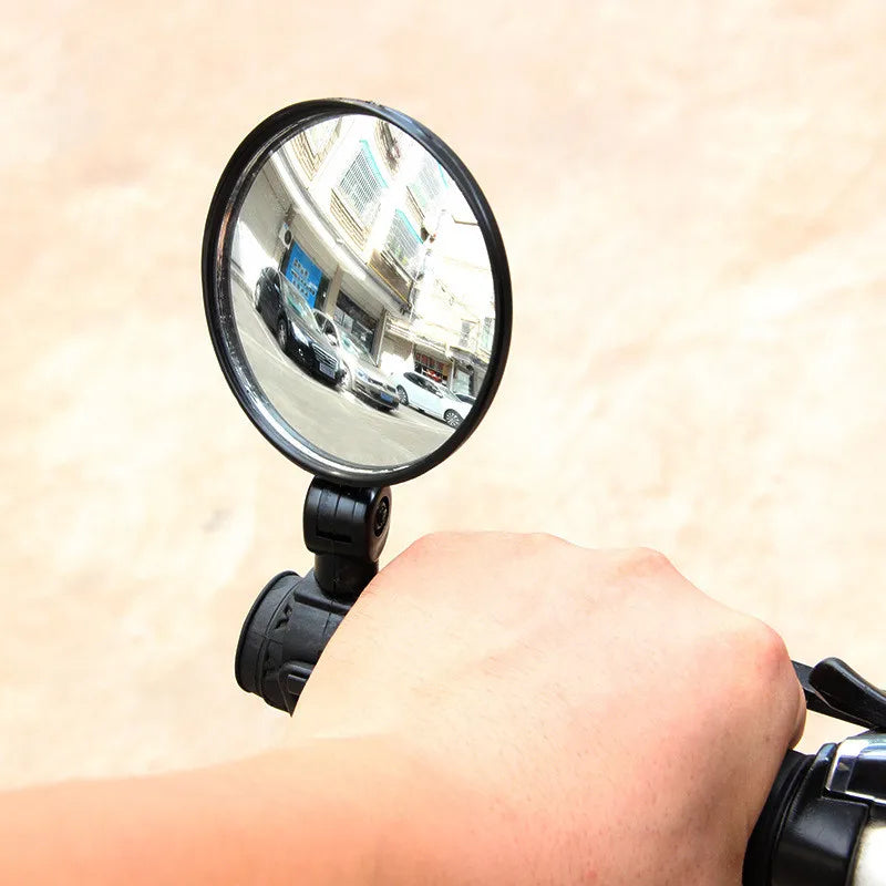 Person holding a scooter or bike handlebar with a round rearview mirror attached