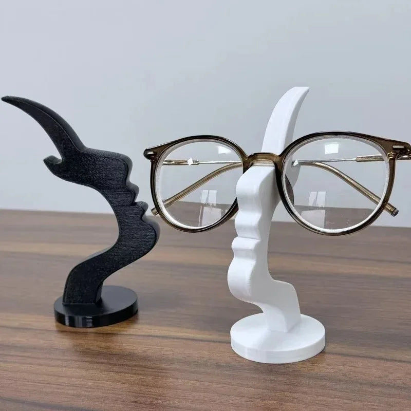 Black and white minimalist face stands, one holding eyeglasses, on a wooden surface