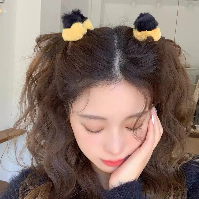 A girl wearing small plush cat ear hair clips with yellow and black colors