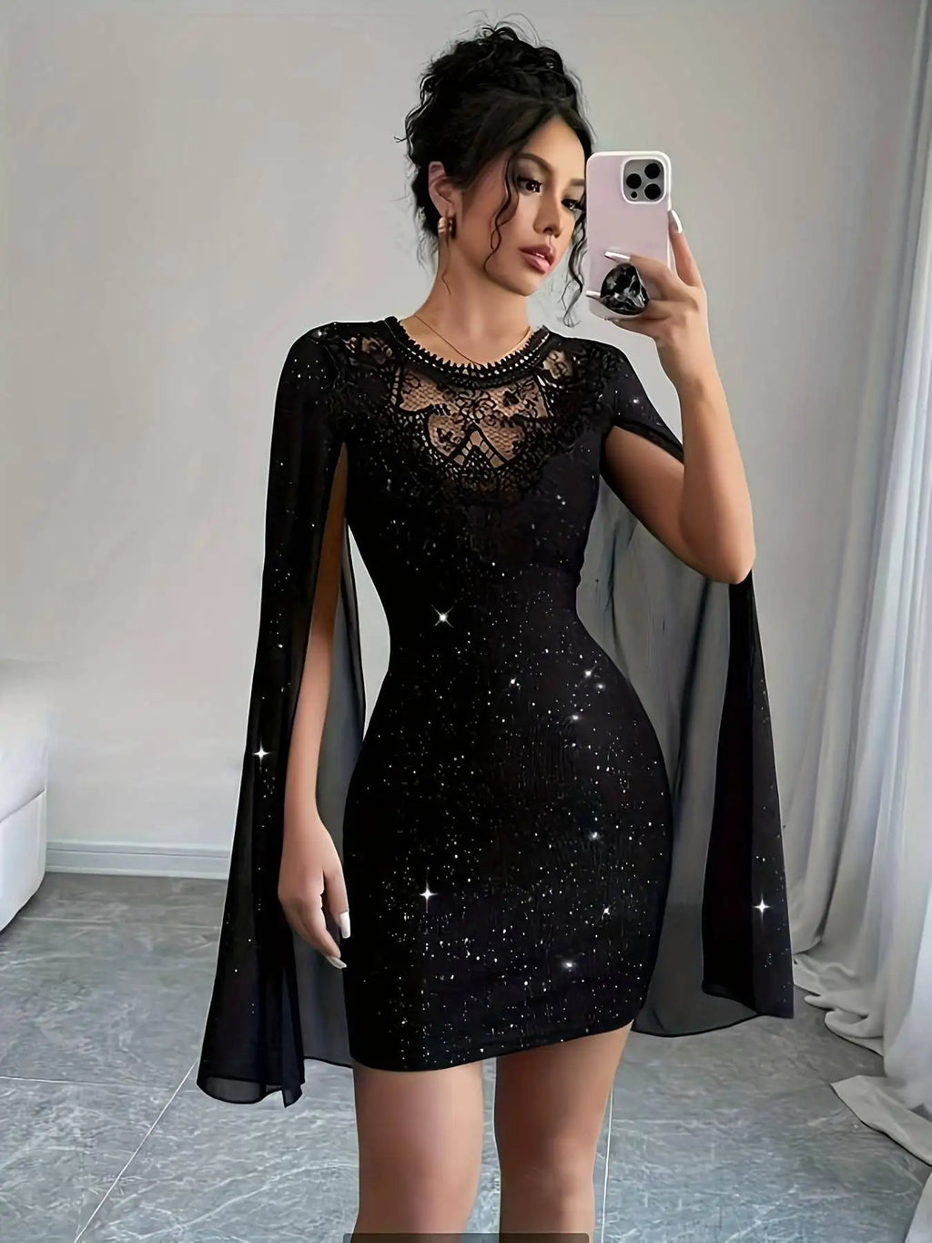 Front view of a woman wearing a black glittery bodycon mini dress with sheer cape sleeves