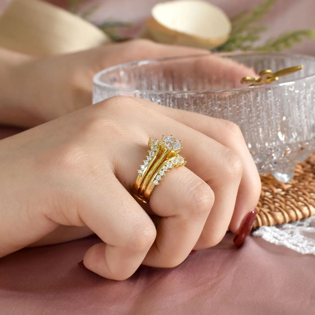 Side view of woman wearing gold plated bridal ring set on her finger