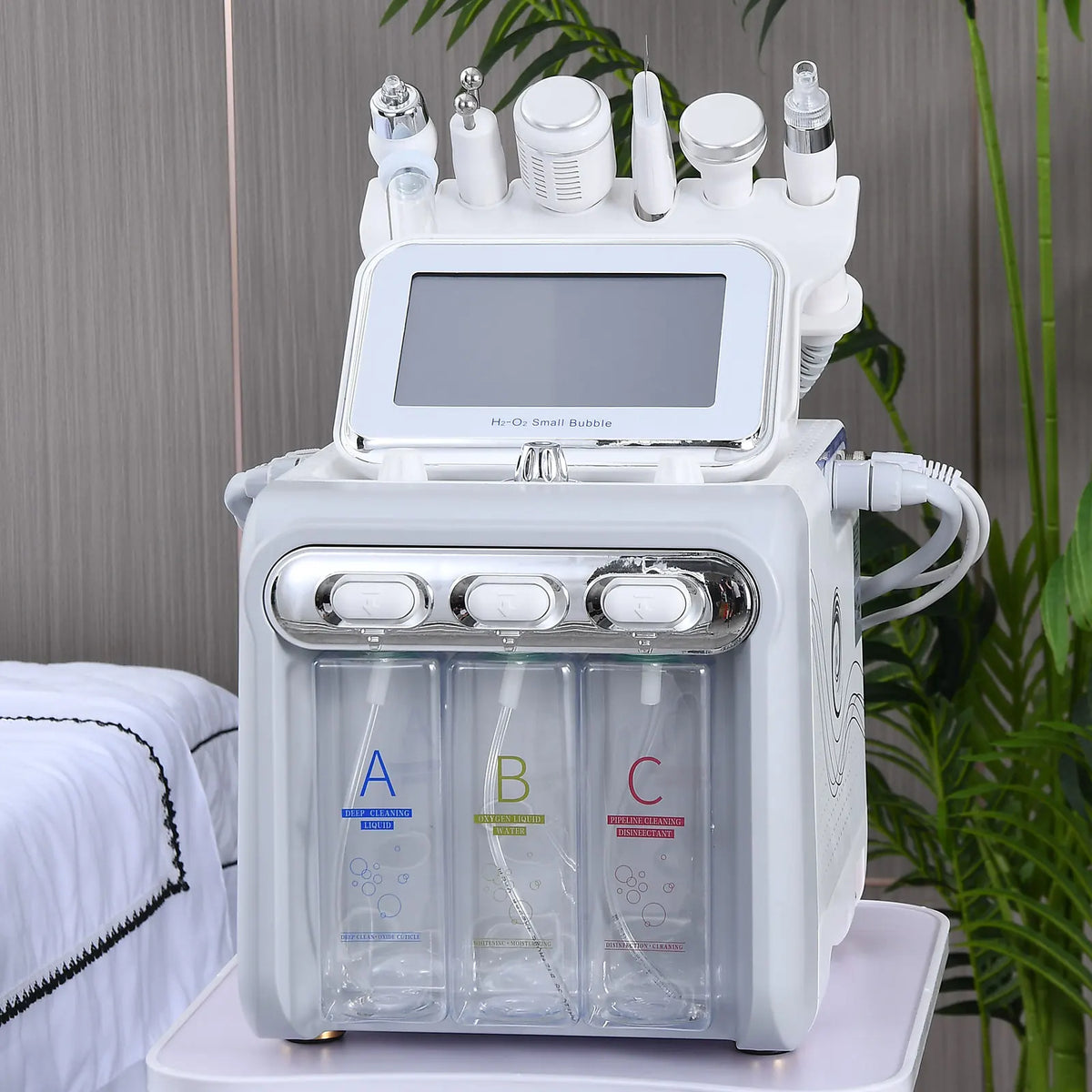 White 6-in-1 hydro-oxygen facial machine with treatment attachments, placed on a salon trolley with greenery background