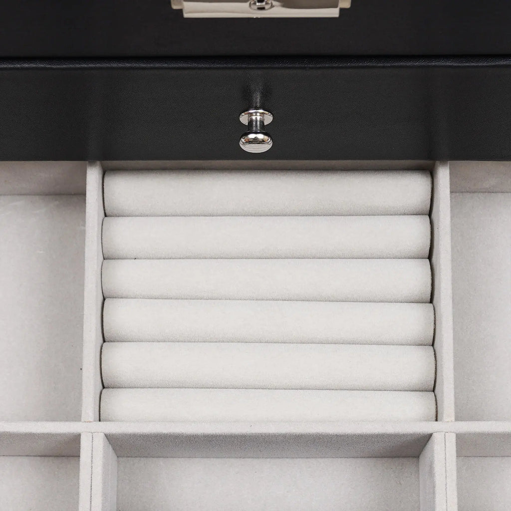 Close up of an open drawer in a jewelry box showing velvet ring rolls.