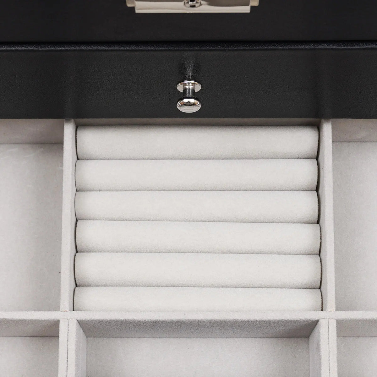Close up of an open drawer in a jewelry box showing velvet ring rolls.