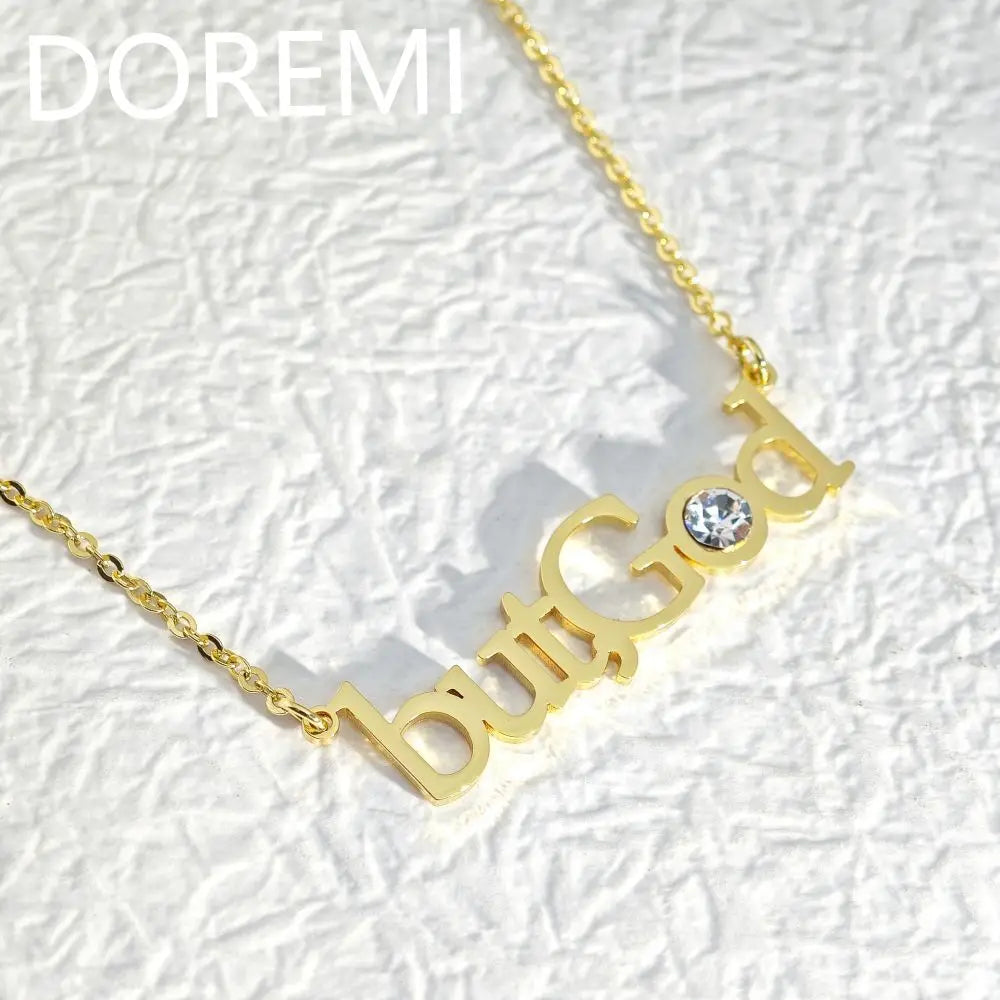 Gold necklace with the words butGod and a crystal on a white textured surface