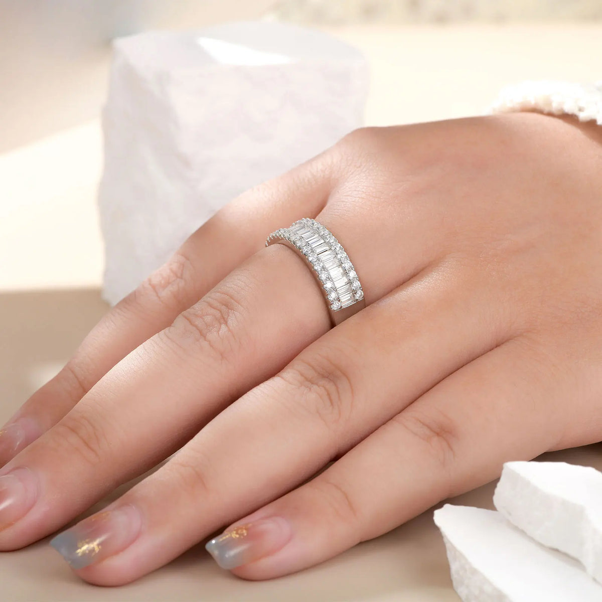 Person wearing a sterling silver wedding band with baguette and round cut stones