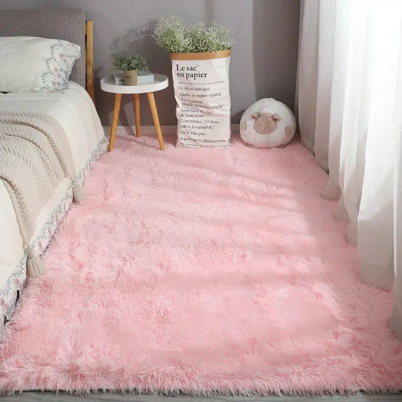 Solid light pink plush area rug in a cozy bedroom setting.