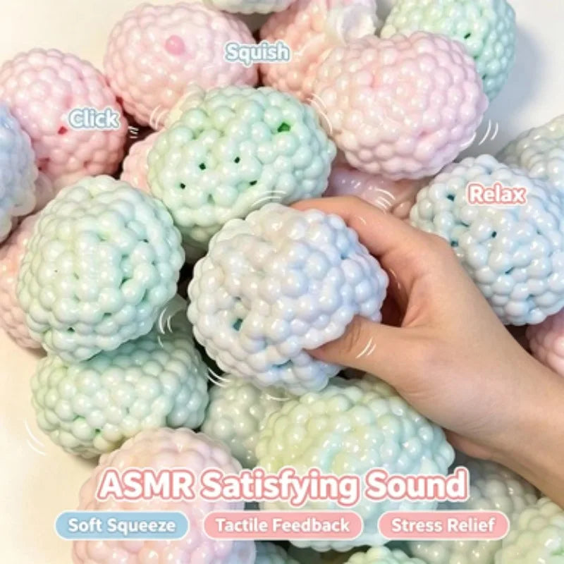 A hand squeezing a pastel coloured squishy bead ball for sensory play