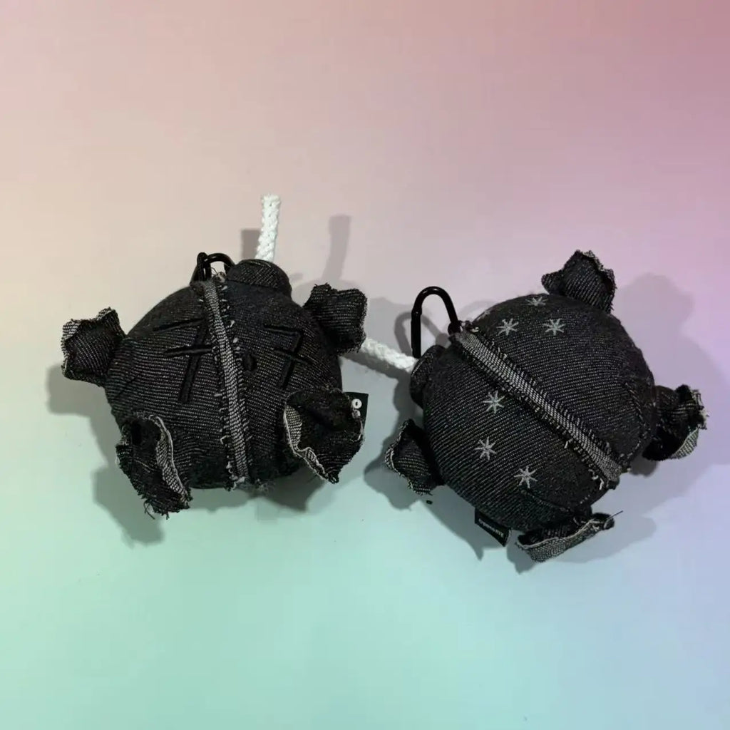Two grey denim plush ball doll pendants with white rope wicks and carabiner clips