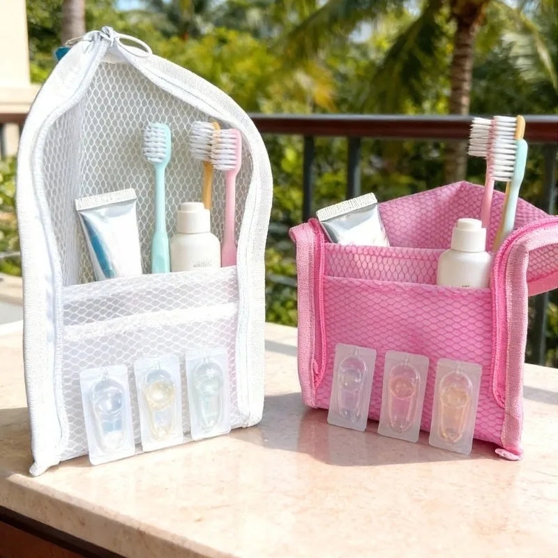 Two standing mesh pouches in white and pink, holding toothbrushes and travel-sized toiletry containers.