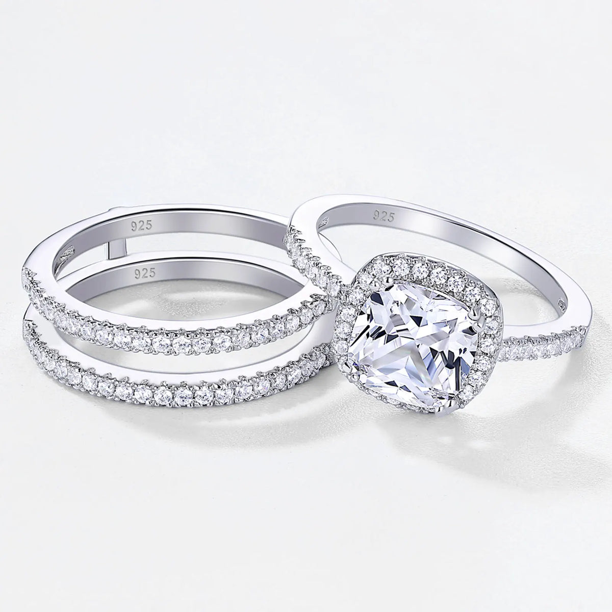 Three-piece wedding ring set featuring a cushion cut halo engagement ring and two matching eternity bands in silver