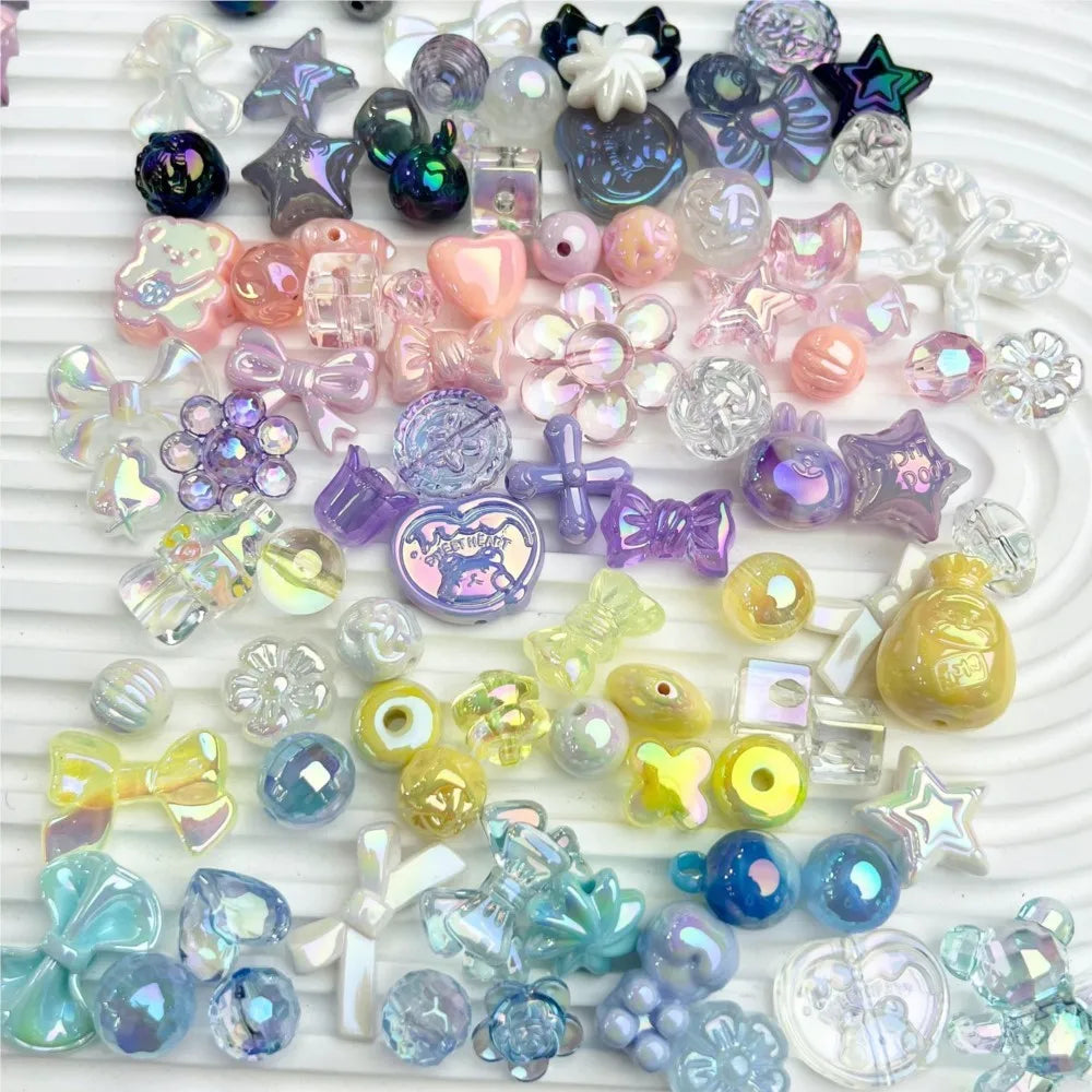 A wide variety of loose acrylic craft beads in shapes of bows, stars, flowers, and animals in iridescent pastel colors.
