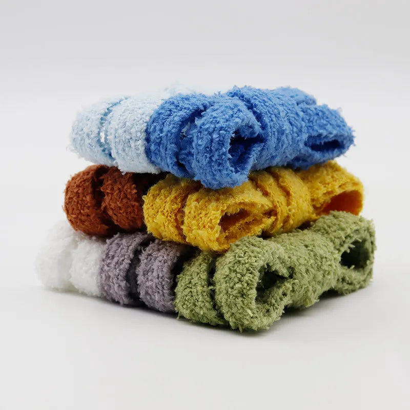 A stacked pile of neatly folded colourful fluffy plush shoelaces on a white background.