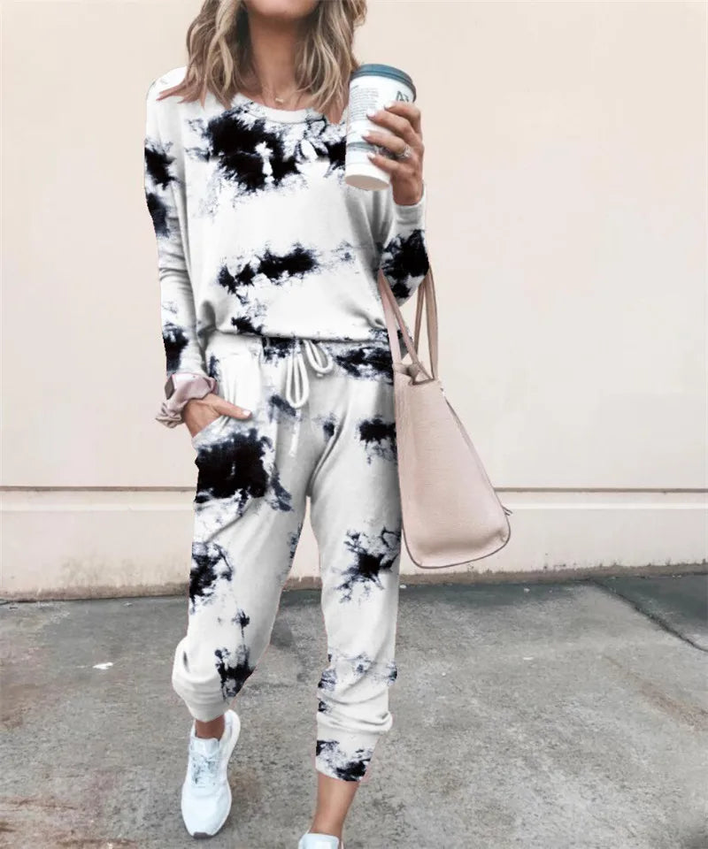 A woman wearing a black and white tie-dye long-sleeve top and jogger pants set, holding a takeaway coffee cup.